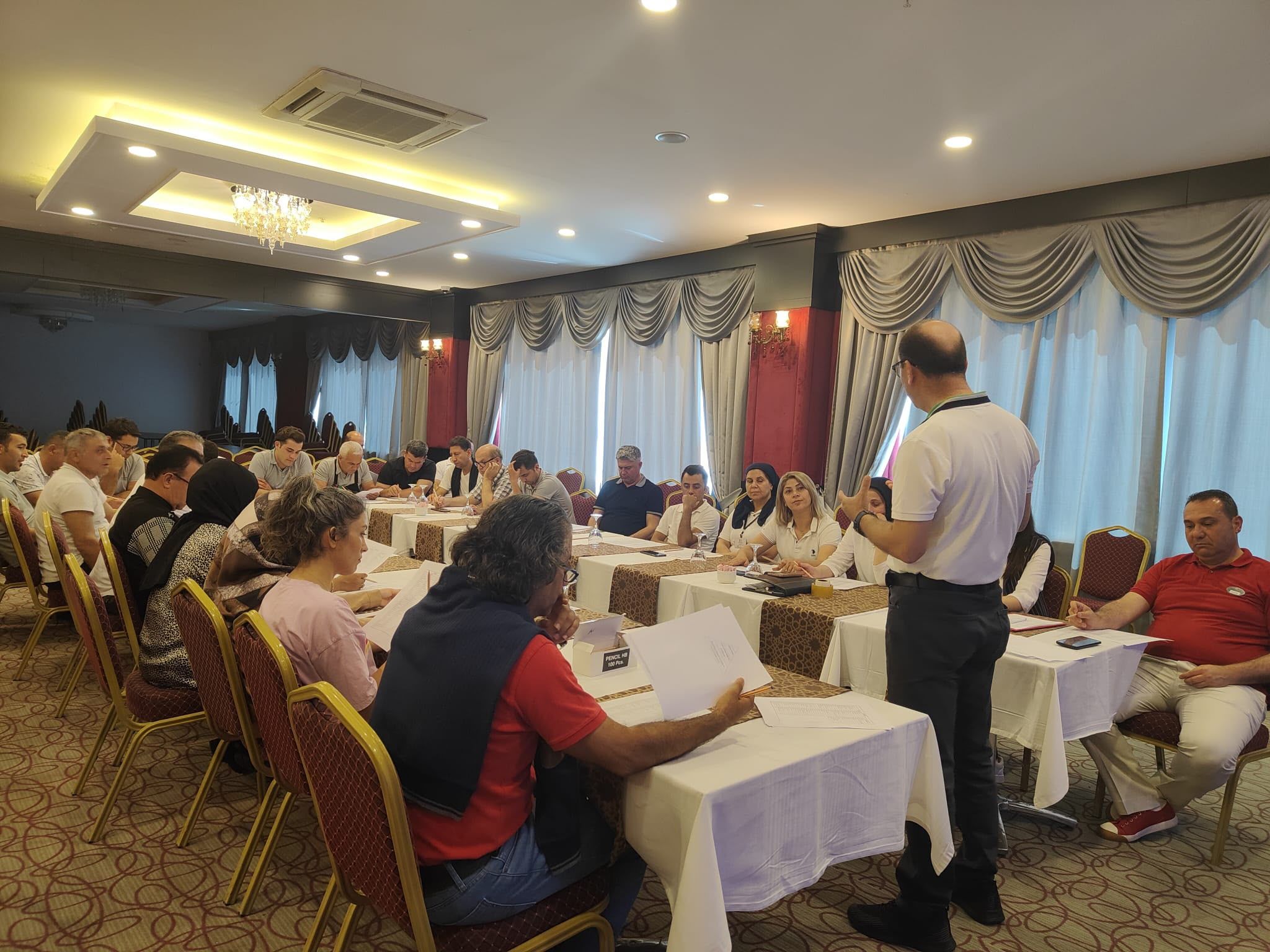 Otel çalışanlarına eğitim salonunda sunum yapan eğitmen