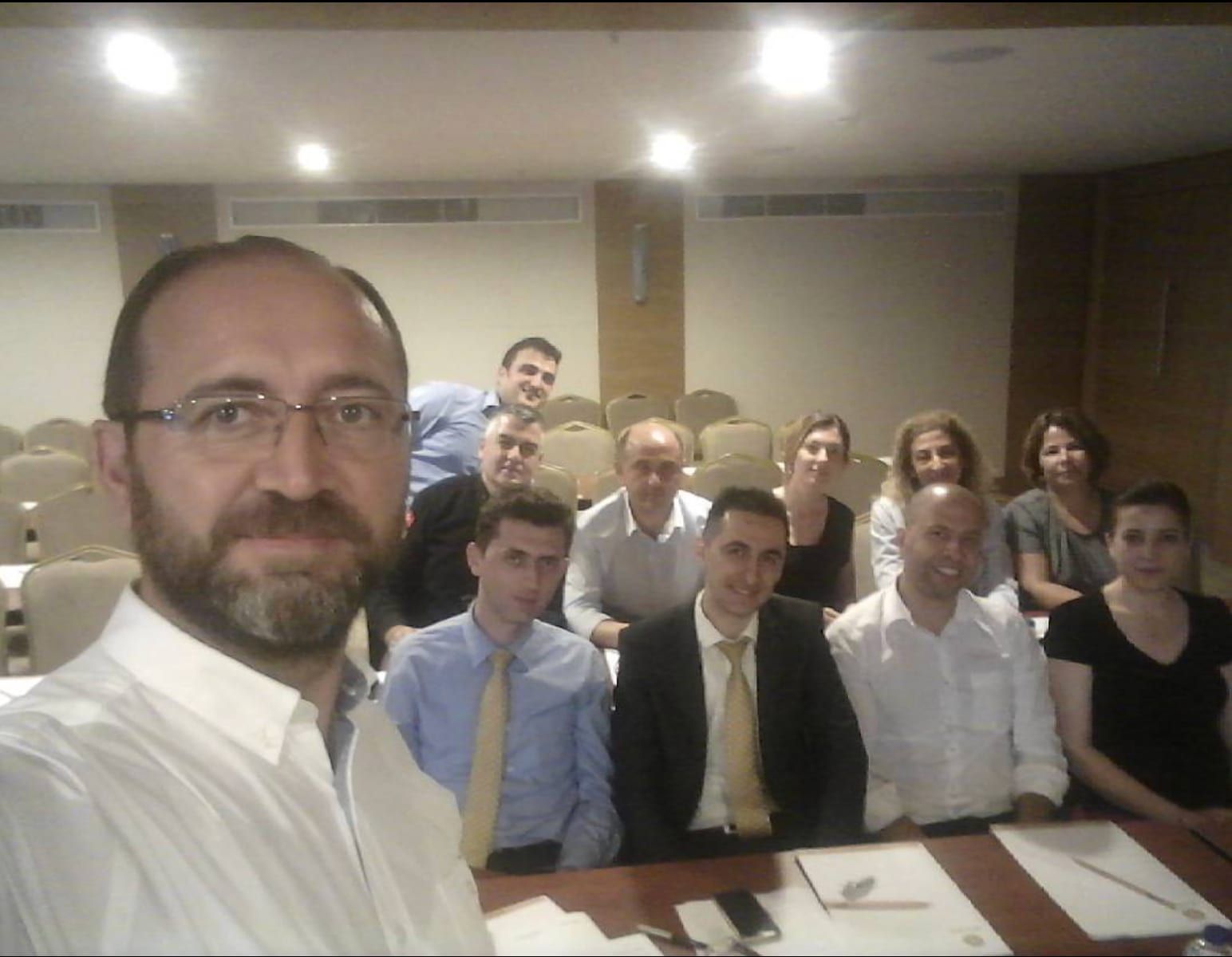 Eğitmen ve katılımcılar bir eğitim salonunda birlikte fotoğraf çekiliyor
