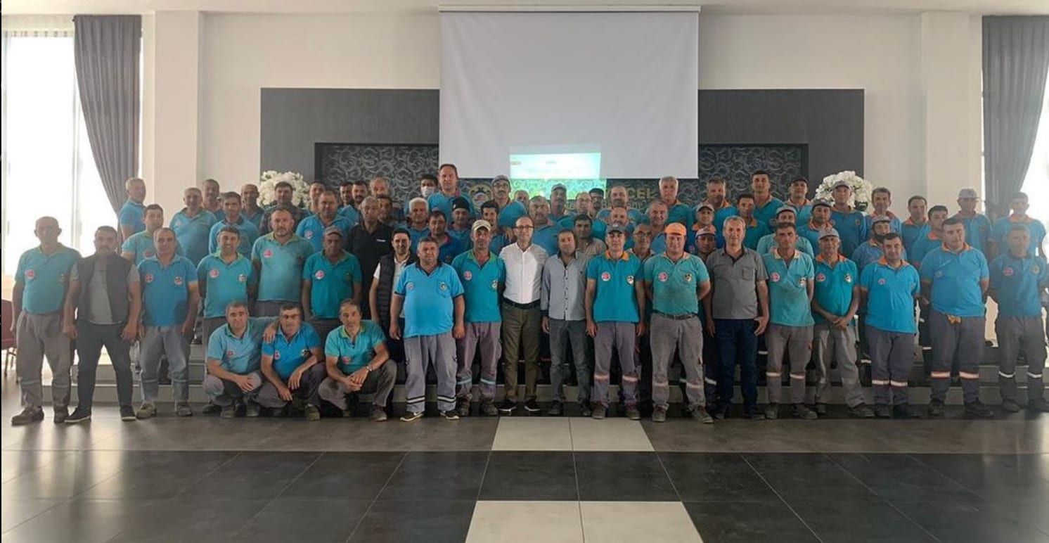 Turkuaz üniformalı ekip ve eğitmen salonda toplu fotoğrafta