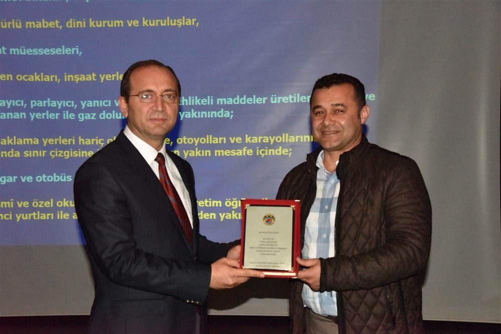 Eğitmen bir kurum yetkilisinden plaket alıyor
